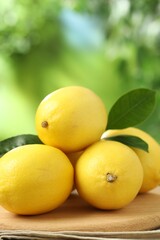 Fresh lemons with green leaves on table outdoors, closeup
