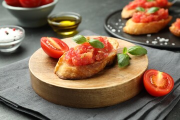 Tasty bruschettas with tomatoes and basil served on black table, closeup