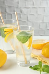 Refreshing water with lemons and mint on white marble table, closeup