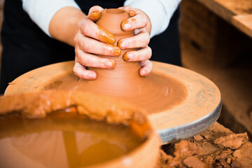 Hands of professional potter molding clay on pottery wheel