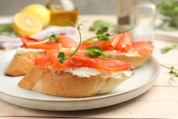 Tasty bruschettas with salmon, cream cheese and microgreens on wooden table, closeup