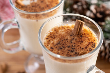 Eggnog with Cinnamon and Christmas Decorations on wooden table. Close up