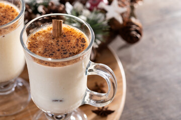 Eggnog with Cinnamon and Christmas Decorations on wooden table. Copy space