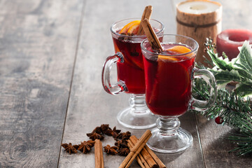 Mulled Wine with Orange and Cinnamon Sticks and Christmas decoration on wooden table. Copy space