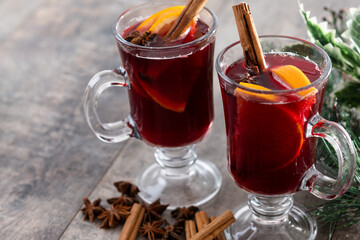 Mulled Wine with Orange and Cinnamon Sticks and Christmas decoration on wooden table