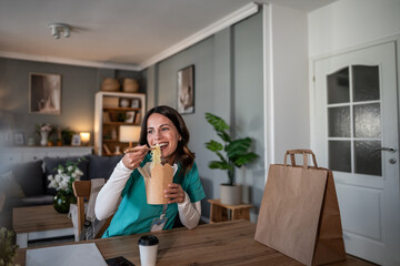 Nurse eating takeout noodles during work break at home