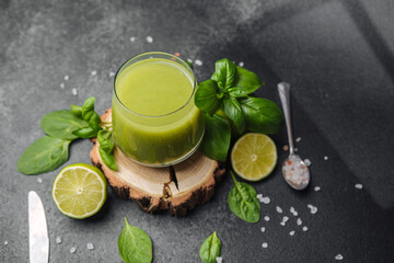 Healthy green smoothie with lime, basil, and spinach on slate surface