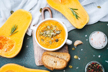 Savory pumpkin soup served with toasted bread and fresh herbs on a rustic dark surface
