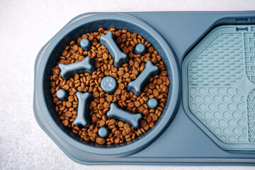 Blue dog slow feeder bowl filled with kibble and bone shapes