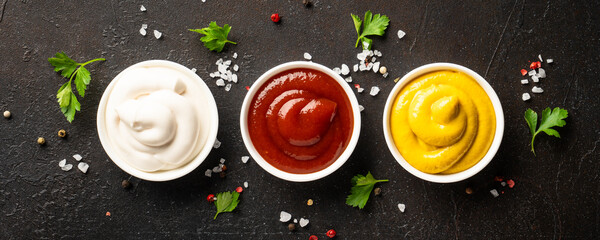 Obraz premium Sauce bowls - mayonnaise, mustard, ketchup on black background.