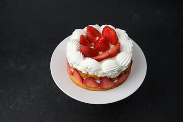 Strawberry shortcake with whipped cream topping on white plate dessert concept for birthday celebration or sweet food advertising