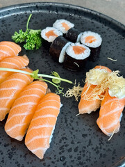 An incredibly delicious selection of sushi and rolls, a variety of fish, raw fish, avocado, wasabi, soy sauce, sesame seeds, chopsticks, Japanese food.