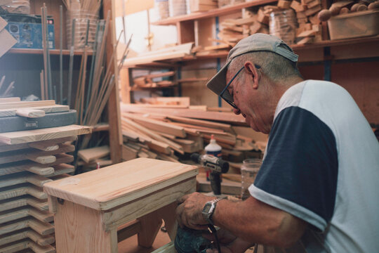 Senior carpenter sanding wooden stool in workshop - Powered by Adobe
