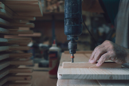 Carpenter's hand drilling wood in workshop
