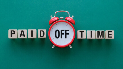 Naklejka premium A red alarm clock with the words Paid Time Off written in black. The clock is surrounded by wooden blocks