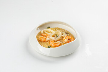 Creamy hummus topped with shrimp, squid rings, and capers served in modern white bowl on white background