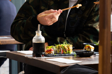 A man eating sushi rolls with chopsticks in a restaurant. Japanese traditional cuisine.