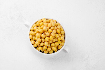 Cooked chickpeas in white bowl on textured dark background for plantbased food, healthy lifestyle or vegan meal concept
