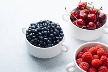 Bowls of raspberries, blueberries and cherries for fruit trio, diet or nutrition concept