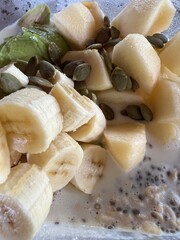 Healthy breakfast, close up of oatmeal with chia, pumpkin seeds and  fresh banana in glass bowl, top view
