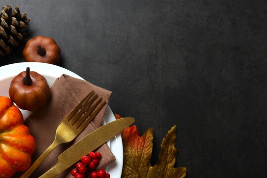 Close-up of table setting with pumpkins, dinnerware, rustic napkin on a plates. Thanksgiving day