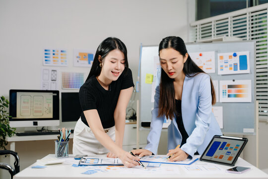 Two UX UI designers collaborating on mobile app wireframes and layouts in modern office. Concept of creativity, teamwork, and digital product design.