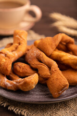 Crunchy biscuit Brushwood cookies on brown wooden, linen textile, cup of coffee, side view, close up, selective focus