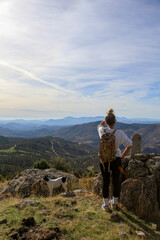 Blonde woman with a bun looking at the mountains after walking along the paths accompanied by her dog