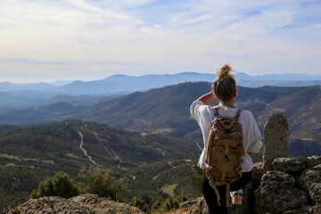 Blonde woman with a bun looking at the mountains after walking along the paths accompanied by her dog