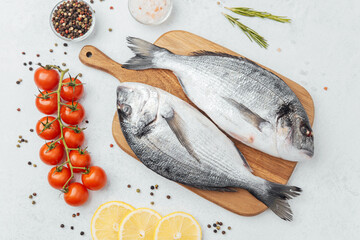 Raw dorado fish with ingredients on wooden cutting board over white background