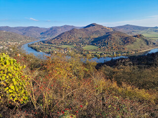 Stunning autumn view of the Elbe River valley from Dubičky viewpoint, Czech Republic. Golden foliage, clear sunlight, and the calm river create a breathtaking landscape.