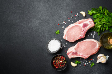 Pork meat. Fresh meat steaks with spices on black background.