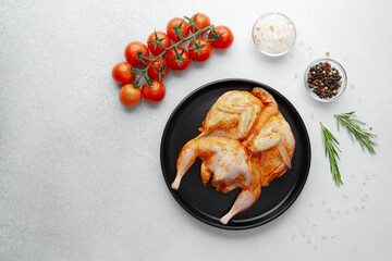 Marinated quail on black plate with tomatoes and spices