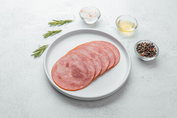 Sliced sausage on white plate with herbs and spices
