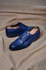 Male blue leather shoes on beige fabric background. Copy space for logo design, advertising. Natural leather accessories for men