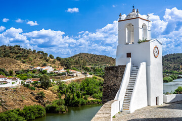 View of Mértola with clock tower above the Guadiana River in Portugal