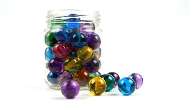 A clear glass jar filled with colorful, translucent spheres, some spilled out, against a bright white background