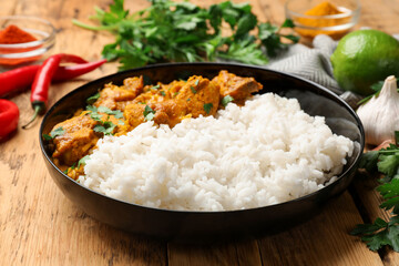 Chicken tikka masala with rice and spices on wooden table, closeup
