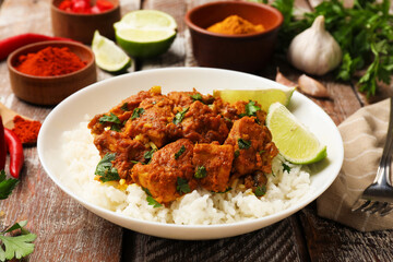 Delicious chicken tikka masala with rice, parsley and lime on color wooden table, closeup