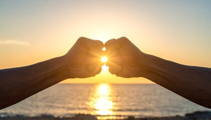 Two clenched fists, facing one another, frame the radiant sun setting over a calm ocean. A brilliant burst of light shines between them