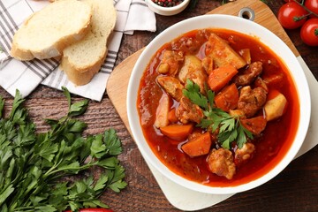 Delicious cooked stew served on wooden table, flat lay