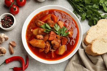 Delicious cooked stew in bowl served on grey table, flat lay