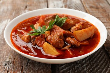 Delicious cooked stew in bowl on wooden table, closeup