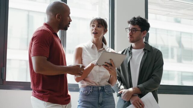 Video of happy business people working with digital tablet while discussing together in the coworking place