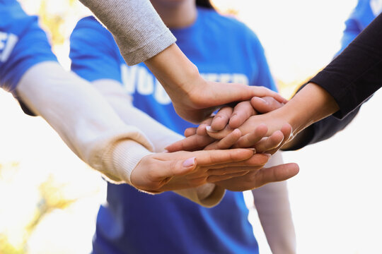 Group of volunteers stacking hands outdoors, closeup - Powered by Adobe