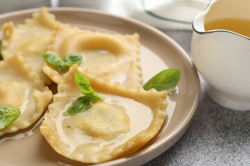 Delicious ravioli with basil served on light grey table, closeup