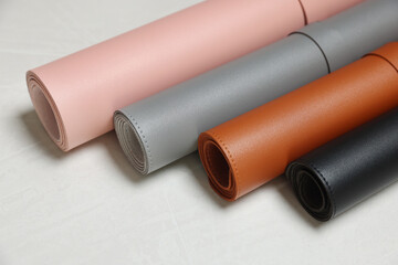 Different rolled computer mats on light grey table, closeup