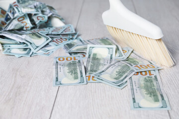 Sweeping dollar banknotes with broom on light wooden floor, closeup