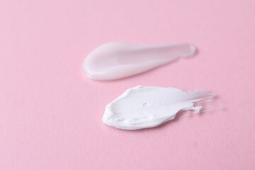 Samples of moisturizing creams on pink background, closeup
