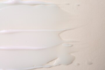 Sample of moisturizing cream on beige background, top view